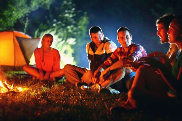 a group sitting around a campfire at night and talking