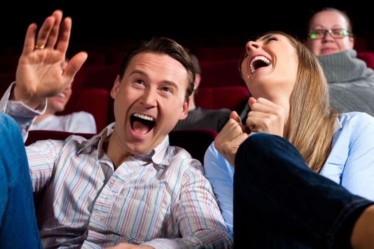 a man and woman laughing in audience seats