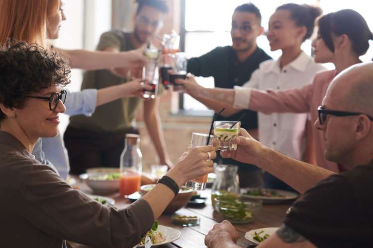 a group of friends around a dinner table, toasting