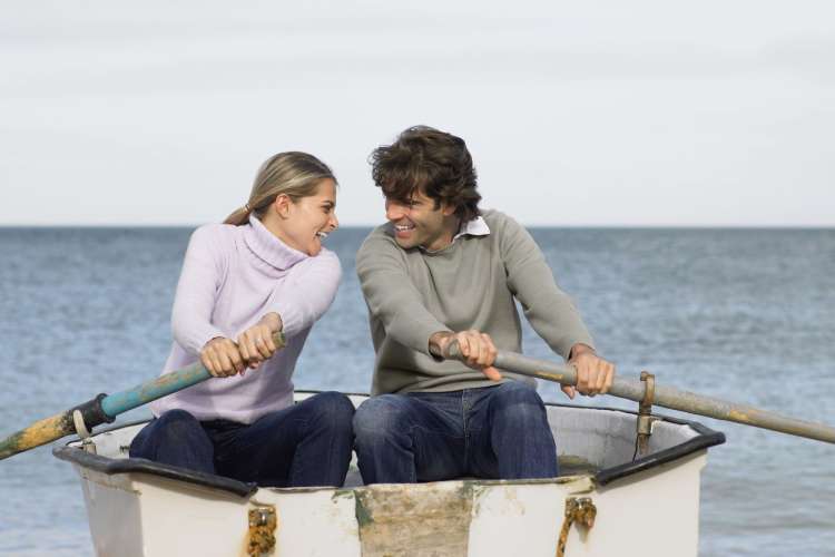 a smiling couple rowing in a rowboat together