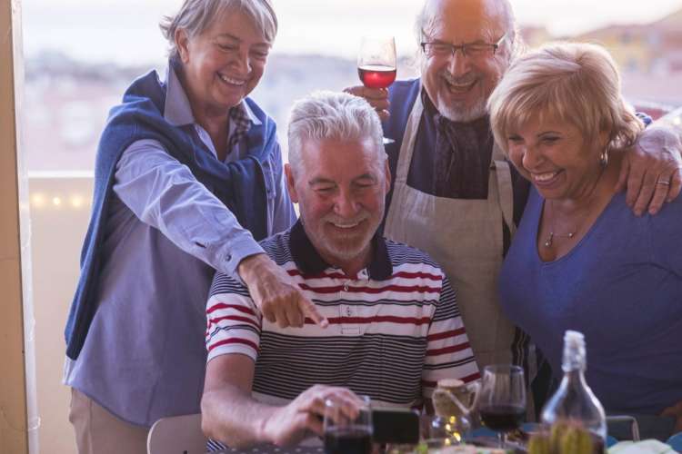 two senior couples looking at photos together on a man's phone