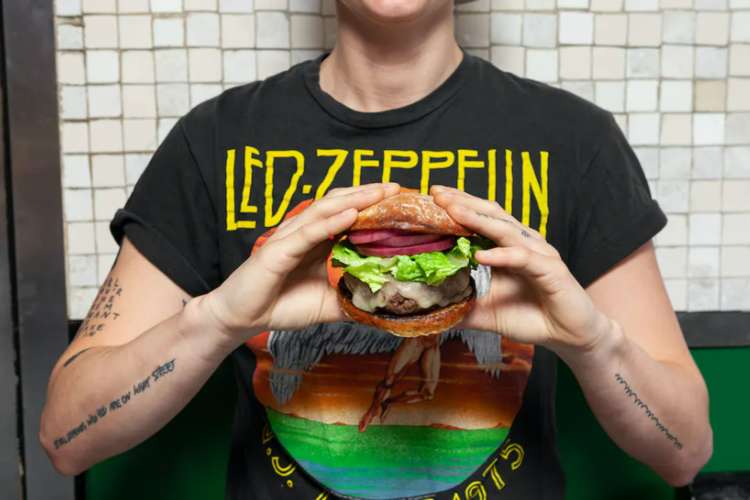 a man holding a thick hamburger