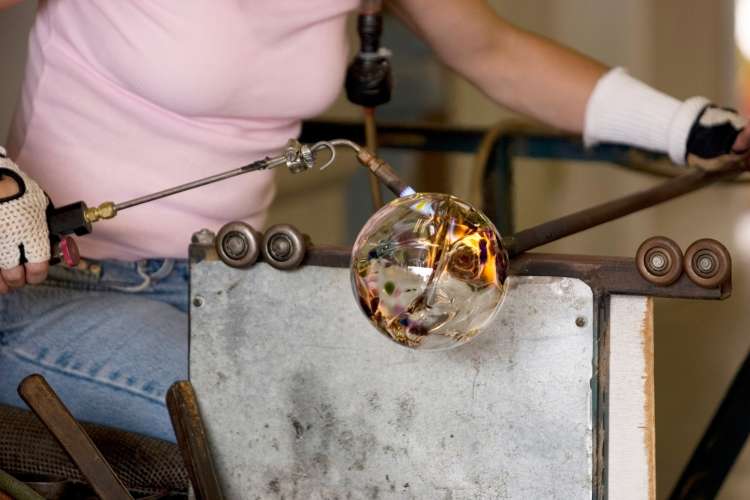 glass artist blowing glass in a studio