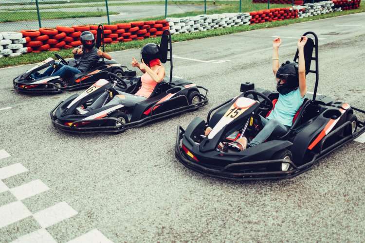 three people in go-karts give each other the thumbs up