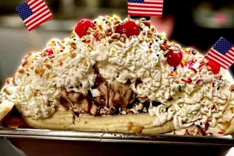 a large ice cream sundae covered in whipped cream and decorate with U.S. flags