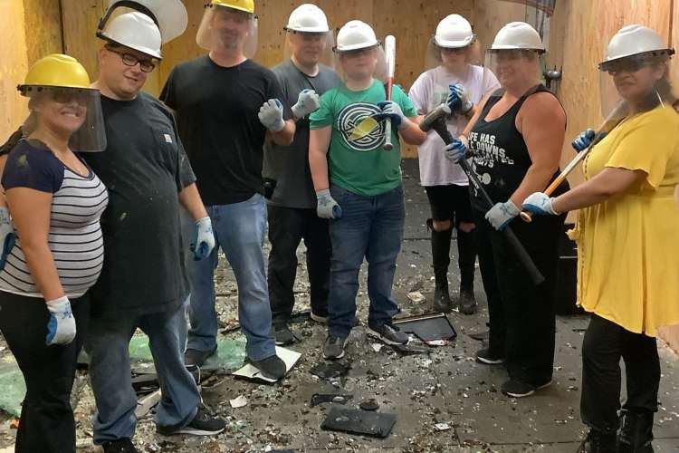 a team in protective gear poses proudly on a floor of broken debris