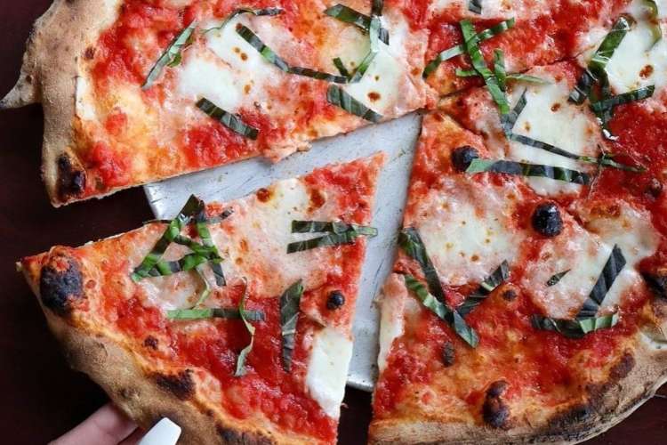 a slice of cheese pizza being removed from a pie 