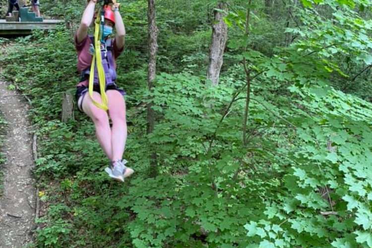 A woman rides down a zipline high in the canopy.