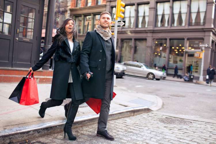 a man and woman exploring an urban area with a shopping bag in hand