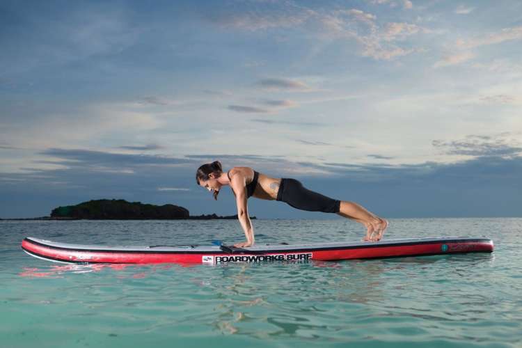 a woman in a pushup position on a paddleboard floating in the water