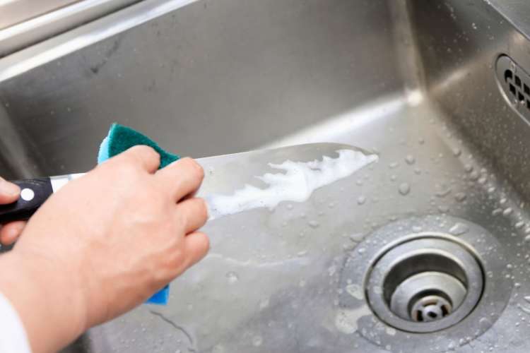 chef washing a knife by hand with a sponge