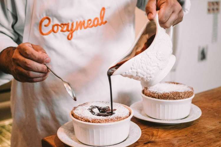 a chef drizzles chocolate on a souffle