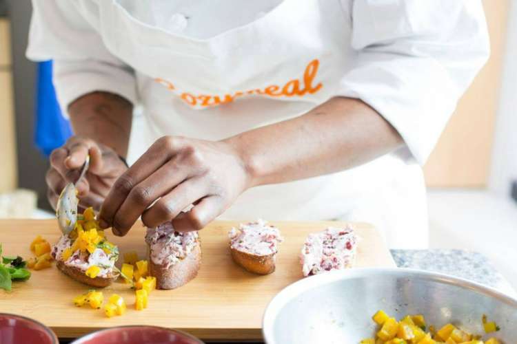 a chef spoons diced yellow peppers onto appetizers