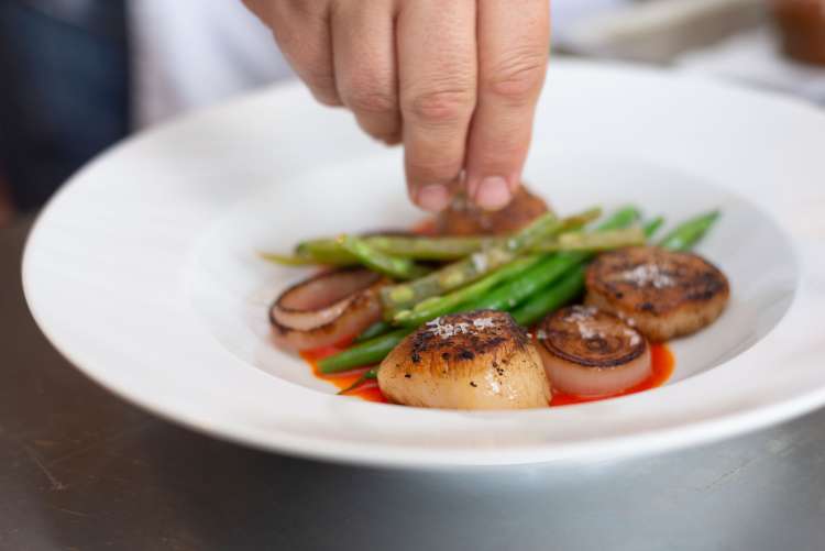 chef plating seared scallops during a private chef experience