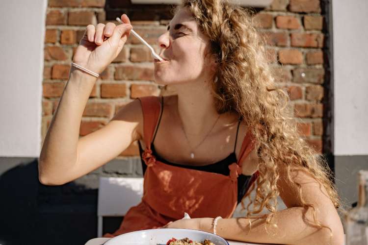 a woman taking a bite off a fork and smiling 