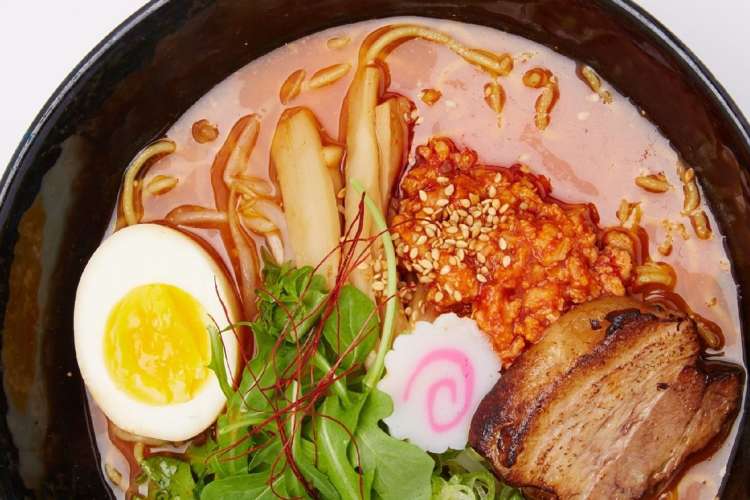 a bowl of red ramen with egg, kimchi and spicy paste