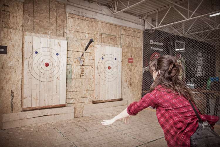 a woman throws an axe into a wooden target