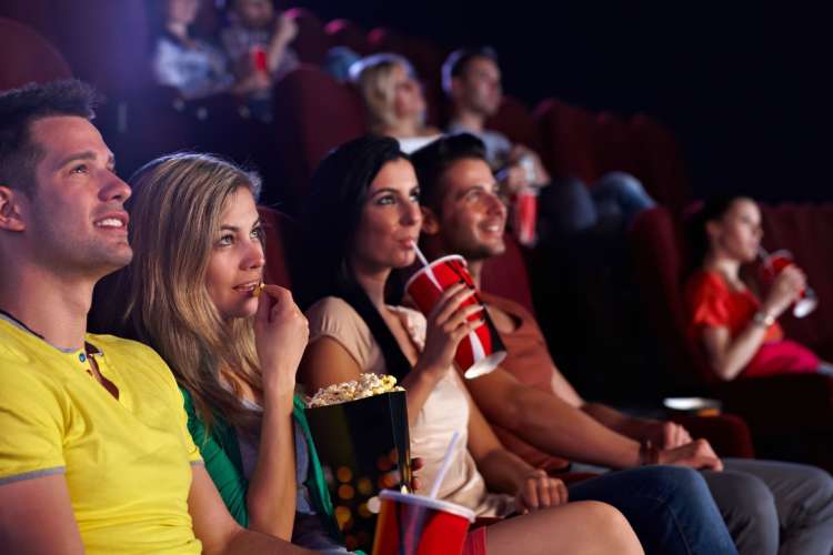 a couple eats popcorn and watches a movie at a cinema