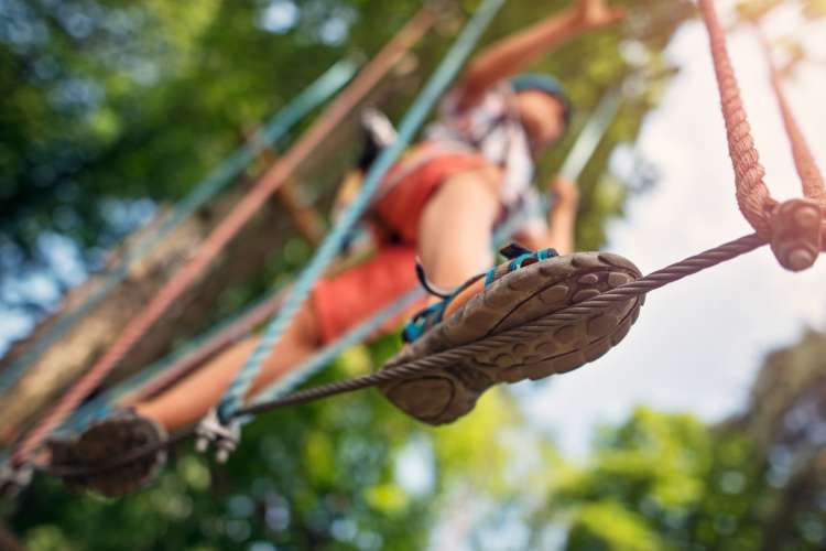 view from below of a man walking a ropes course