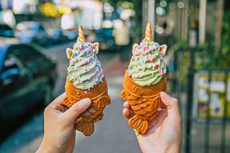 swirls of green ice cream with unicorn horns and sprinkles in a fish shaped cone