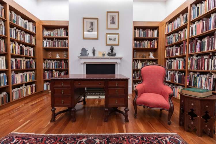 a red armchair among statues and books in Toronto Public Library