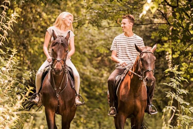 a couple riding horses in the countryside