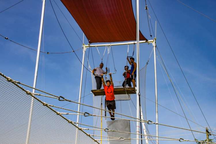 man in a red shirt poised on a platform before swinging on a trapeze