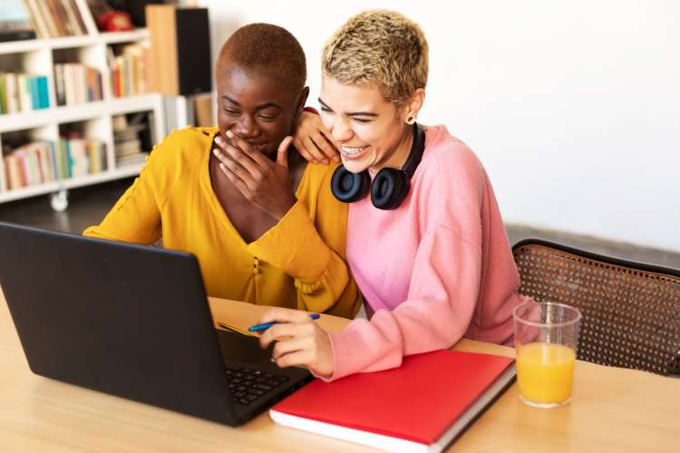 two short-haired women with a laptop laughing 