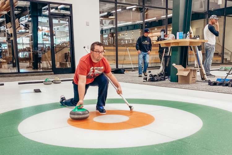 man practicing curling on an ice rink 