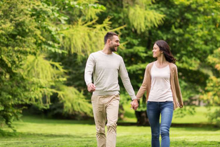 a couple walking hand in hand in a park