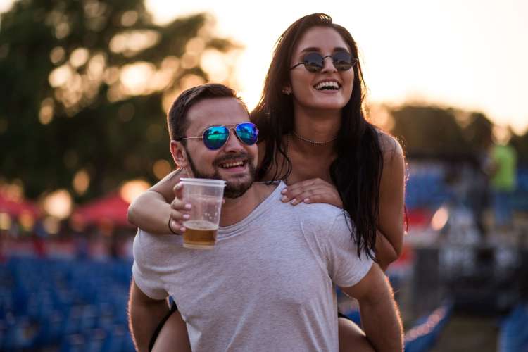 a man carries a woman on his back at a music festival