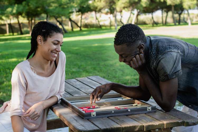 a couple playing a board game together on a table outside