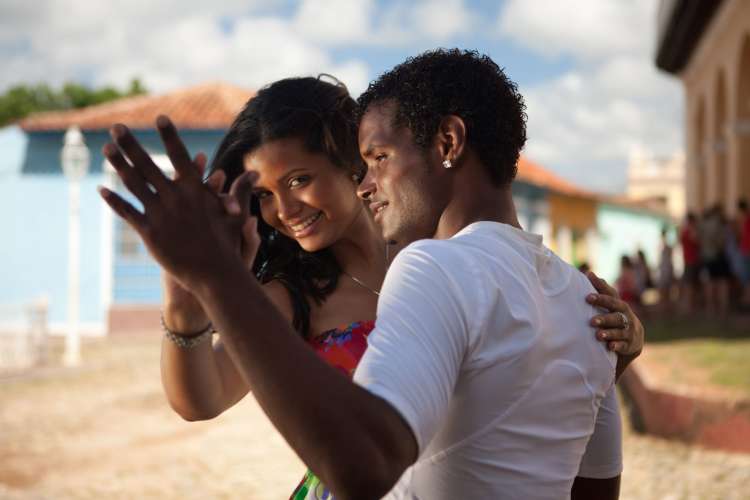 a black-haired woman and man dance in a sunny area