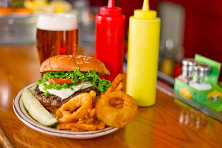 a cheeseburger with onion rings and bottles of condiments