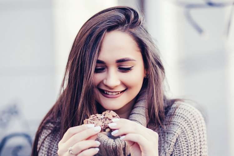 a smiling young woman holding a cookie