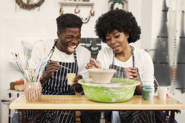 A man and woman taking a pottery class together, which is a fun first date idea