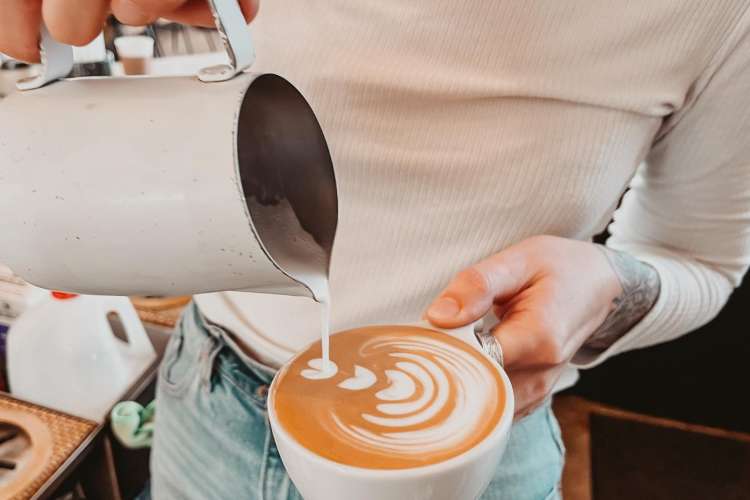 barista pouring a latte at merit coffee co. 