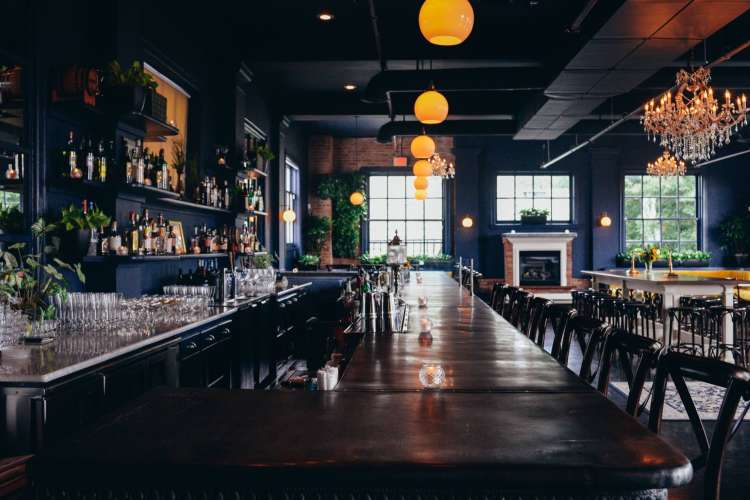 a large bar and dining area with blue walls and chandeliers