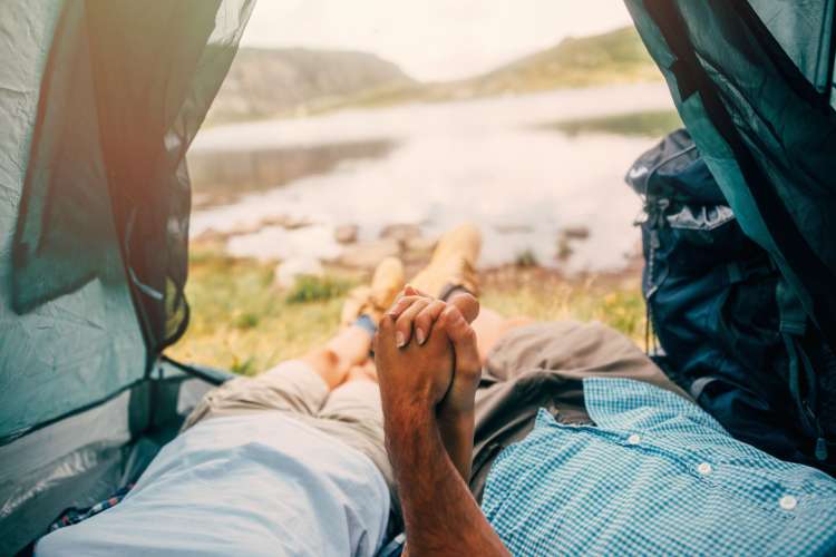 A close-up of two people's hands being held together in a camping tent