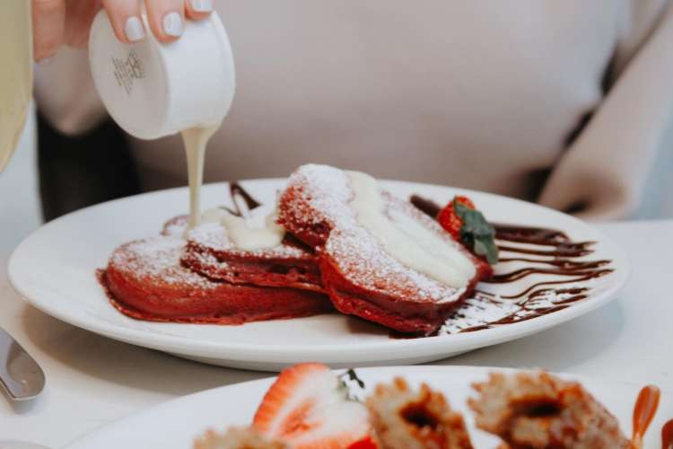 sauce being poured onto a plate of pancakes