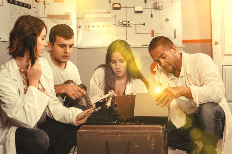 five people pondering over clues in an escape room