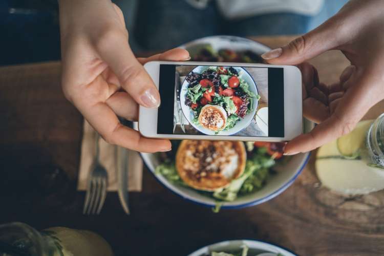 a plate of salad seen through the screen of a smartphone