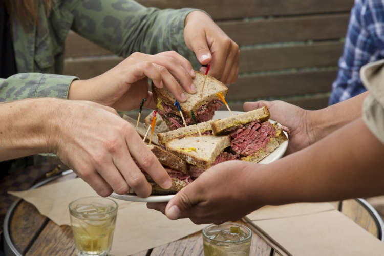 people being served a beef sandwich on a food tour