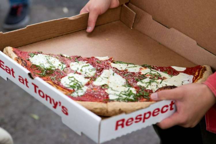 an open box of pizza being offered on a food tour