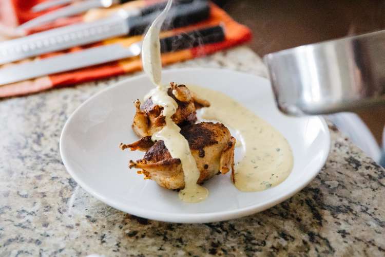 chef plating chicken with cream sauce