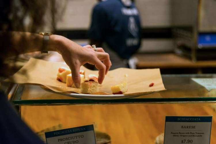 a hand picking up a pastry sample in a bakery