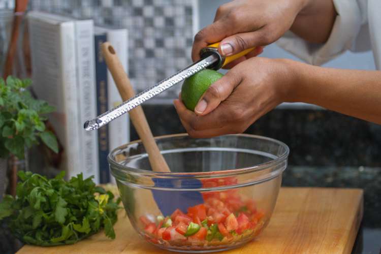 chef zesting lime over tomatoes during a private chef experience