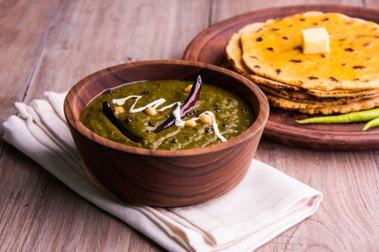 a bowl of vibrant green saag with a side of roti