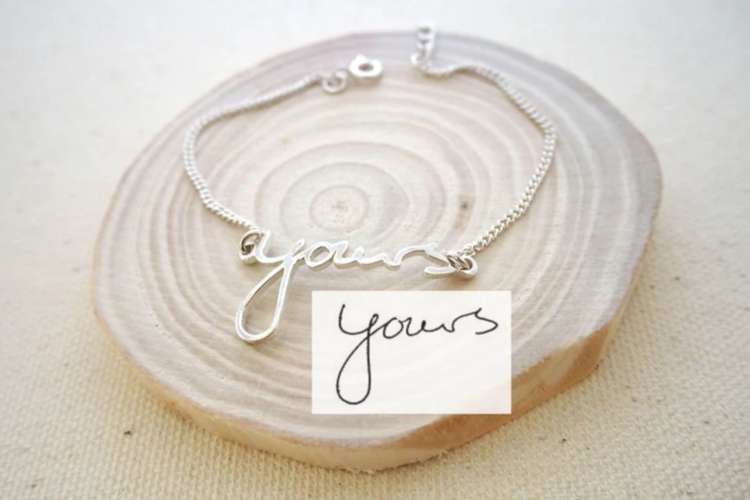 a necklace with a pendant shaped in handwriting that reads Yours