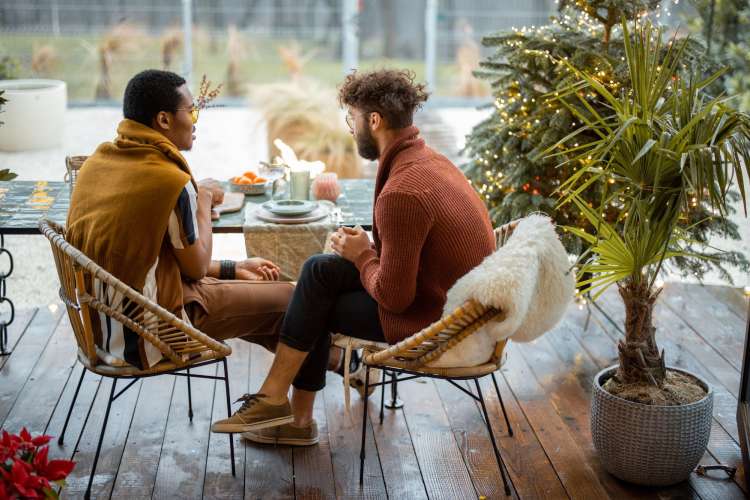 a couple sits outside on their backyard patio eating dinner